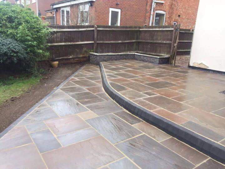 Indian sandstone patio with charcoal block-paved border