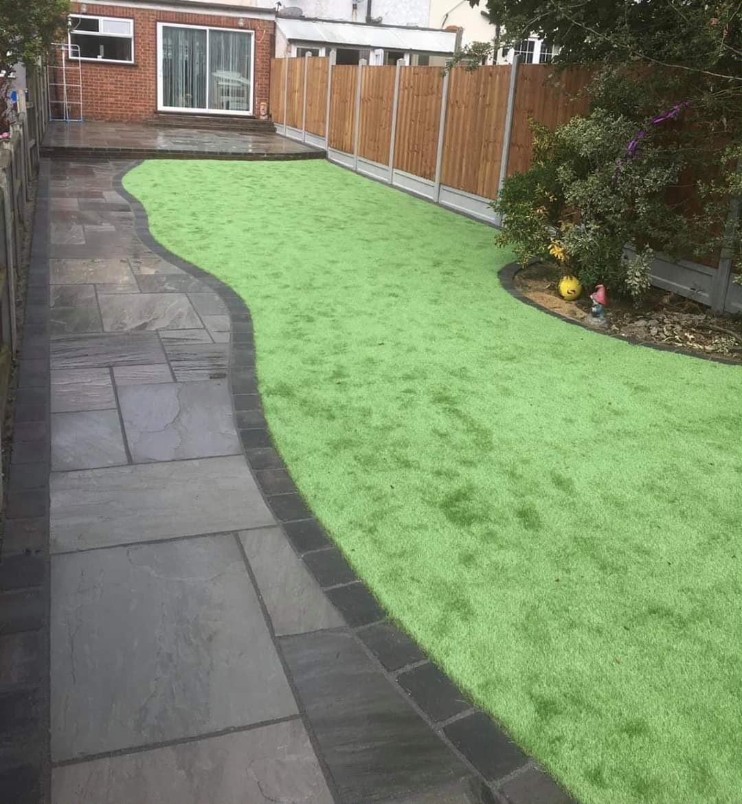 Rich green artificial lawn with sandstone border