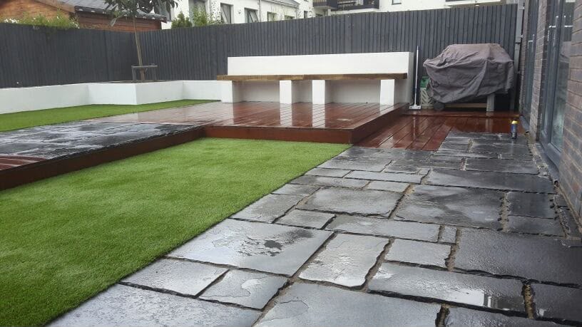 Dark patio, artificial grass and rendered walls at the rear of a home