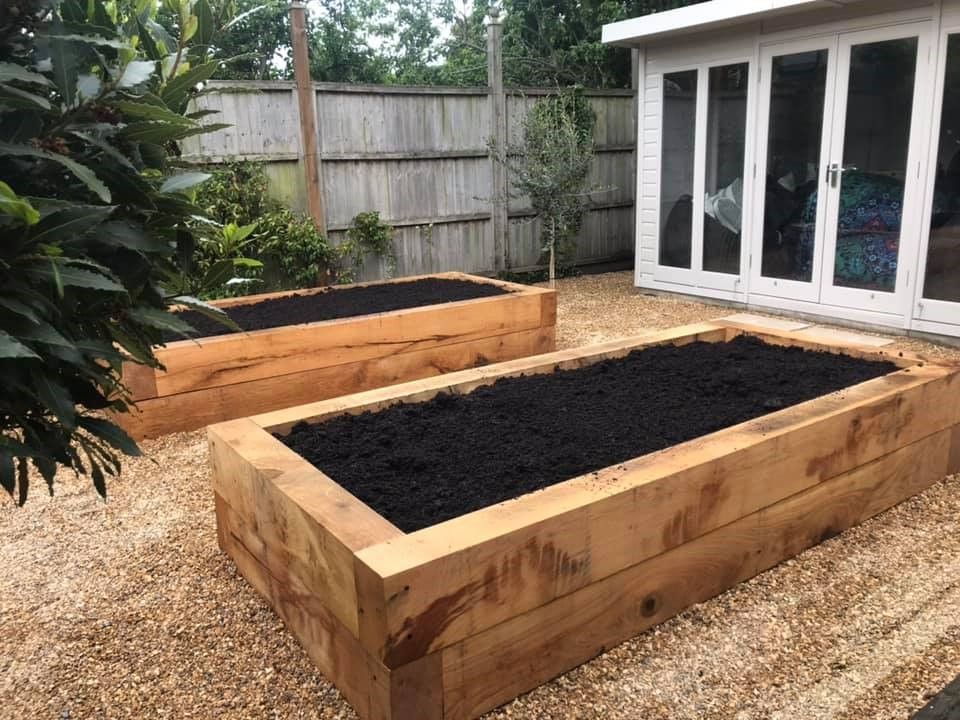 Two oak-sleeper raised beds beside a garden studio