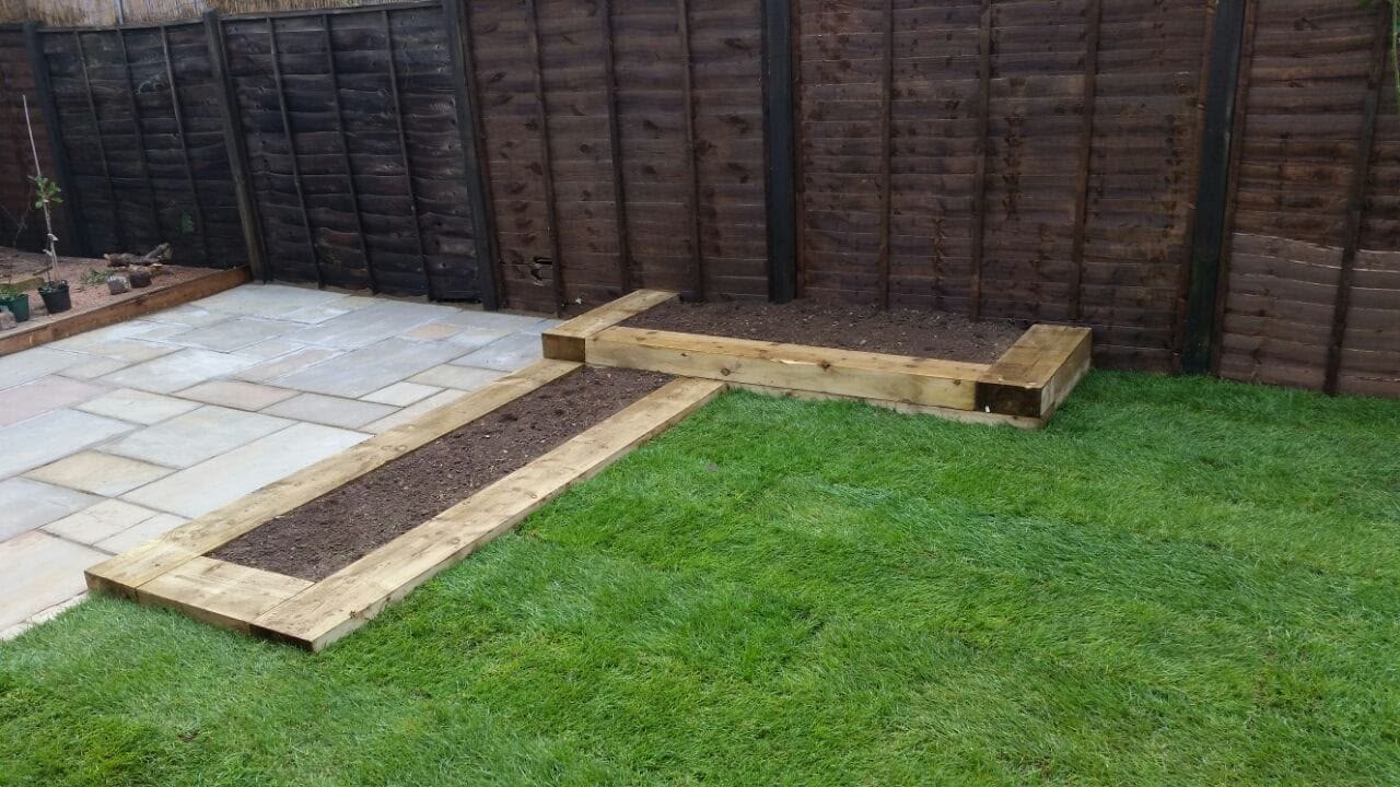 Striped lawn with sleeper raised beds and sandstone edging