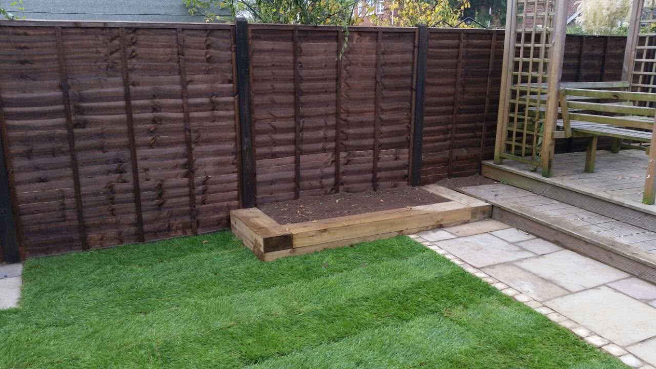 Feather-edge timber fencing with a fresh lawn and trellis
